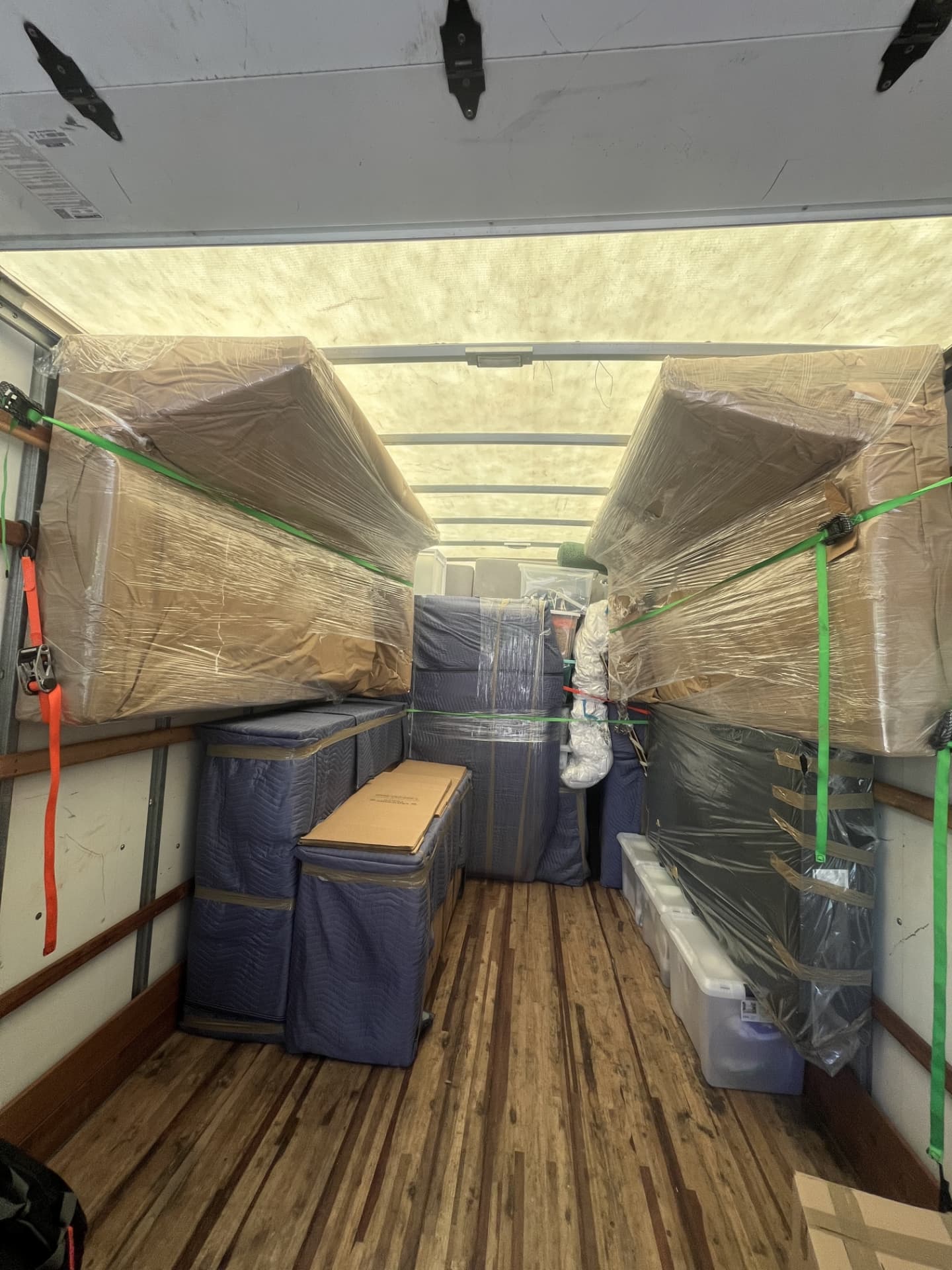 Wrapped couches secured with straps inside a moving truck